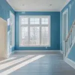 A freshly painted interior room with blue walls, white trim, and an open window allowing airflow to support interior paint drying and curing.