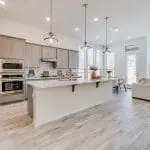A modern kitchen with freshly painted gray cabinets, white quartz countertops, and stainless steel appliances showing the results of professional kitchen cabinet painting.