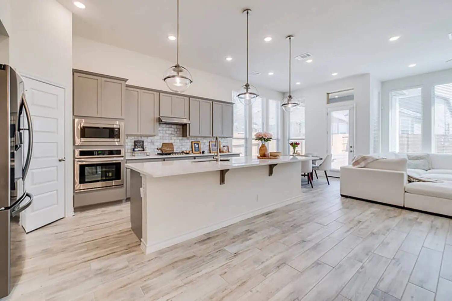A modern kitchen with freshly painted gray cabinets, white quartz countertops, and stainless steel appliances showing the results of professional kitchen cabinet painting.
